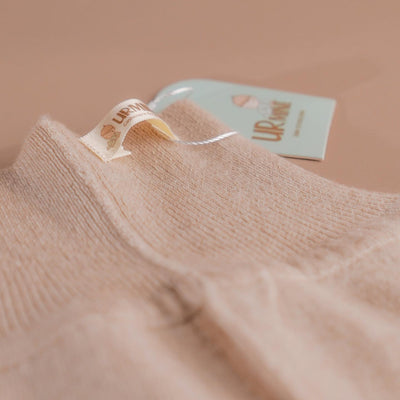 Soft beige baby cashmere pants featuring a ribbed waistband and ankle cuffs, designed for ultimate comfort and warmth.