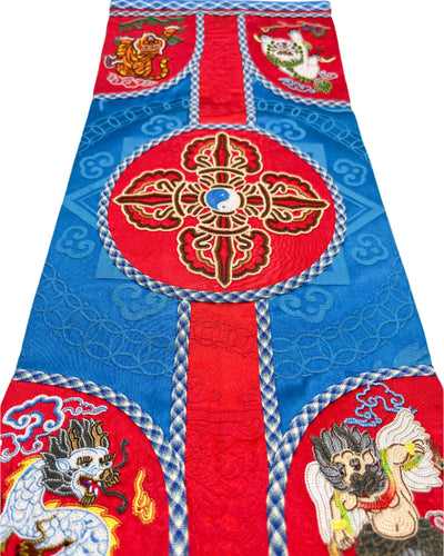 The Four Mighty Creatures, the Natsagdorj symbol, the Vajra, and the Spiral patterns are intricately embroidered. The design is finished with fishbone stitching and double-layered coin braid stitching for decoration on a vibrant red and blue silk.