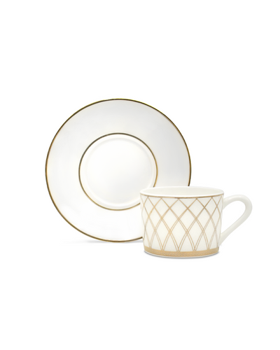 It showcasing a saucer and a mug. A saucer with a round golden edge and golden imagery of the iconic "khana" lattice wall of the traditional Mongolian ger.
